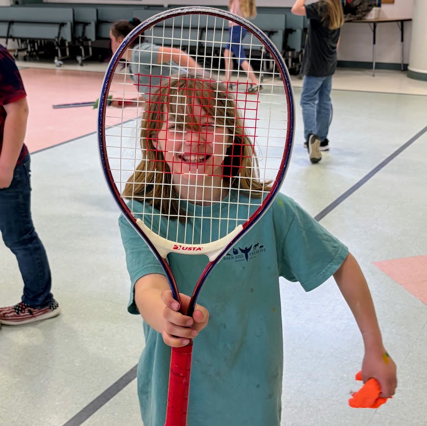 A student holds up a tennis racket